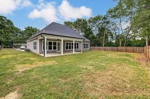 A single-story house with a covered patio area, a fenced yard, and a clear sky.