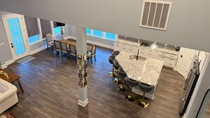 A modern kitchen with a marble island, white cabinetry, and a dining area with a wooden table and chairs. - Beautiful Escape, Mins from Carowinds & Lake Wylie (Charlotte)