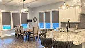 A modern kitchen with a large island, bar stools, and pendant lighting. - Beautiful Escape, Mins from Carowinds & Lake Wylie (Charlotte)
