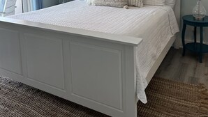Ein Schlafzimmer mit einem Bett, einem Deckenventilator, zwei Wandleuchten und zwei gerahmten Kunstwerken.