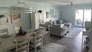 Ein modernes Wohnzimmer mit Essbereich, einer Couch und einem Deckenventilator.