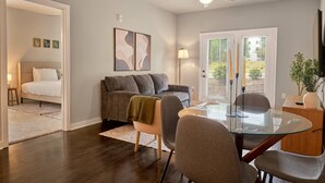 Ein modernes Wohnzimmer mit einem Glastisch, grauen Sofas und einem Deckenventilator.