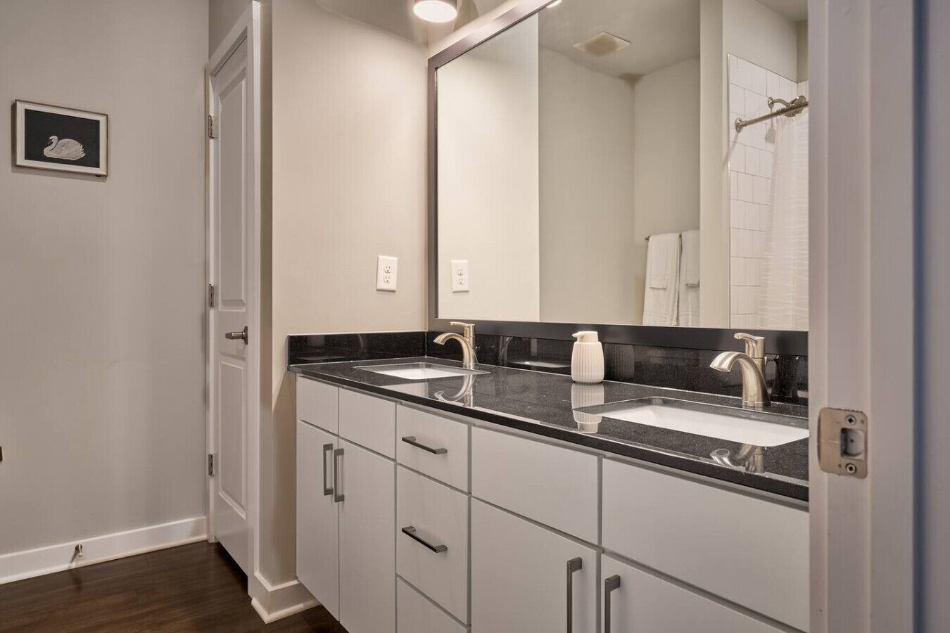 A modern bathroom with two sinks, a large mirror, and a shower area.