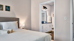 A bedroom with a bed, bedside table, lamp, and framed pictures on the wall.