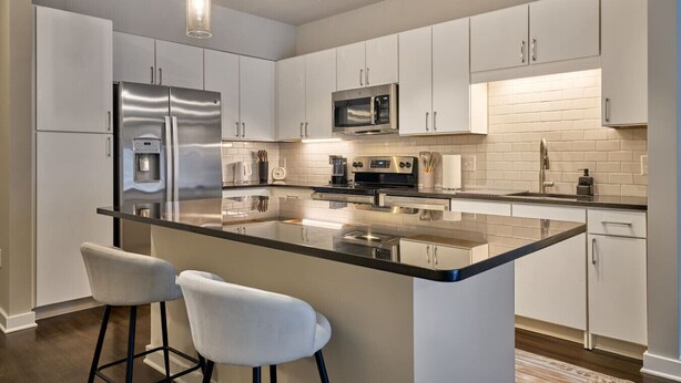 A modern kitchen with a central island, stainless steel appliances, and pendant lighting.