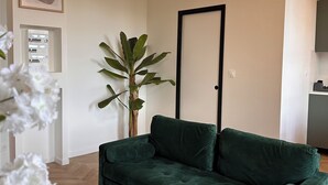 A modern living room with a green sofa, a wooden coffee table, a potted plant, and a ceiling fan. - Design & Comfort apartment ! Sleeps 4 (Périgueux)
