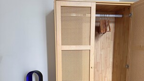 A wooden wardrobe with a woven door, a hanging rack, and a small drawer. - Design & Comfort apartment ! Sleeps 4 (Périgueux)