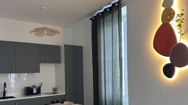 A modern kitchen with dark cabinets, a wooden dining table, and a teal sofa. - Design & Comfort apartment ! Sleeps 4 (Périgueux)