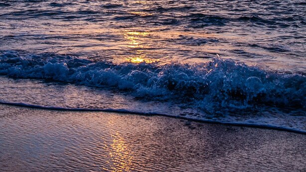 A sunset over the ocean with waves on the shore. - Charming 1-bedroom apartment centrally located to all that Bermuda has to offer (Devonshire)