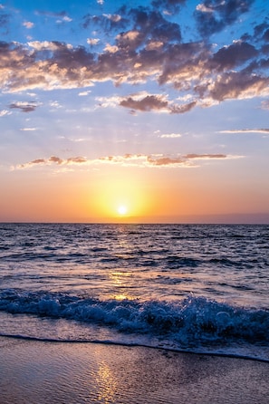 Un atardecer sobre el océano con olas en la orilla.