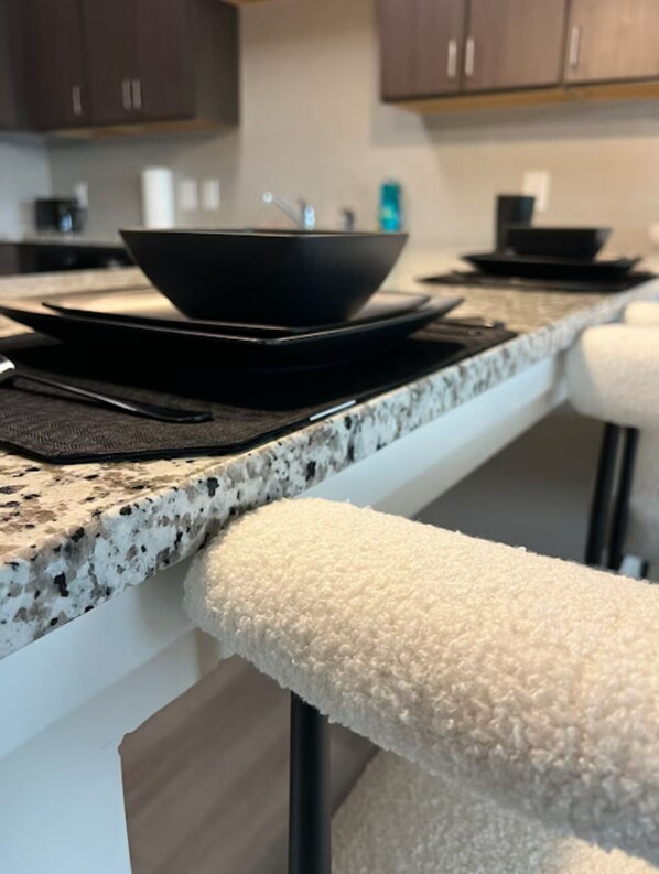 A kitchen counter with a black bowl, a black tray, and a black spatula.