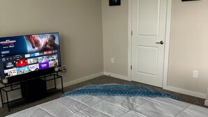 A bedroom with a bed, a TV on a stand, and a door.