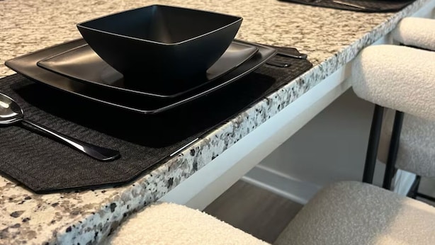 A kitchen island with a black bowl on a mat, a sink, and a faucet.