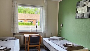 Ein Studentenwohnheimzimmer mit zwei Einzelbetten, einem Schreibtisch und einem Stuhl.