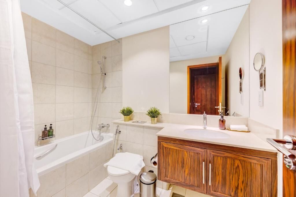 Een moderne badkamer met bad, toilet, wastafel en een houten opbergmeubel.