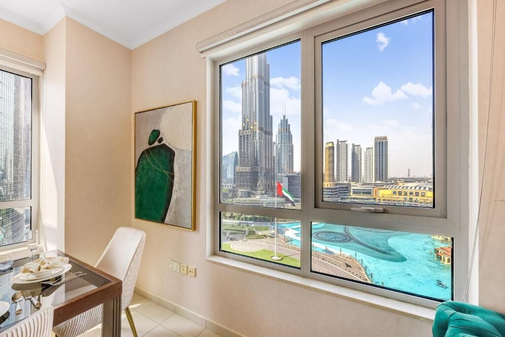 A modern living room with a large window offering views of a city skyline and a body of water.