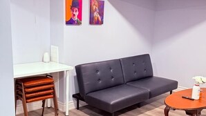 Un salon moderne avec un canapé en cuir foncé, un bureau blanc et une petite table ronde agrémentée d’un vase.