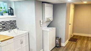 Une cuisine moderne avec des armoires blanches, un plan de travail en bois, un lave-linge et un sèche-linge intégrés, et un dosseret carrelé.
