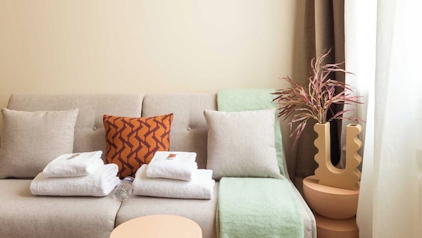 A modern living room with a sofa, a round table, and a decorative vase. - Port-royal Residence-magnificent Apartment -1br-4p (Paris)