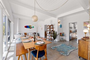 A spacious dining area with a wooden table, chairs, and a chandelier.
