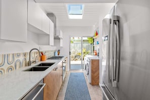 A modern kitchen with a skylight, a washing machine, and a refrigerator.