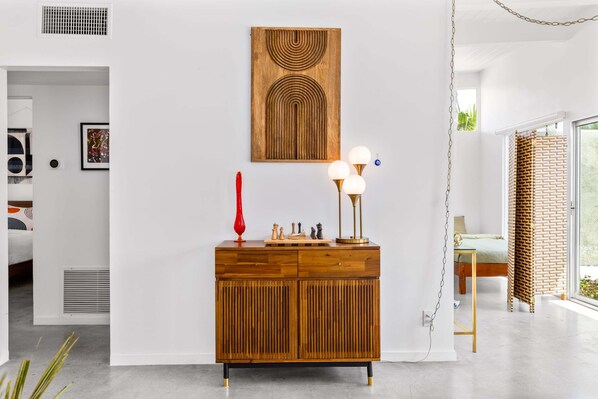 A modern living room with a wooden cabinet, a red vase, and a chess set.