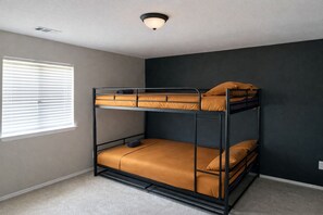A bunk bed with a headboard, a window with blinds, and a ceiling light fixture.