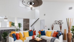 A modern living room with a white sofa, colorful cushions, a wooden coffee table, and a geometric rug. - Kitchen Foosball Fenced Yard Parking (Kyle)