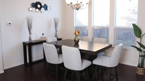 A dining area with a dark wooden table, four upholstered chairs, a vase with flowers, and a chandelier. - Media Room Pool Table Office Room Kitchen (Wylie)
