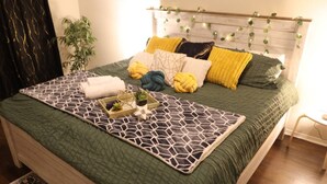 A neatly made bed with a geometric patterned bedspread, multiple pillows in various colors, and a bedside table with a lamp. - Media Room Pool Table Office Room Kitchen (Wylie)