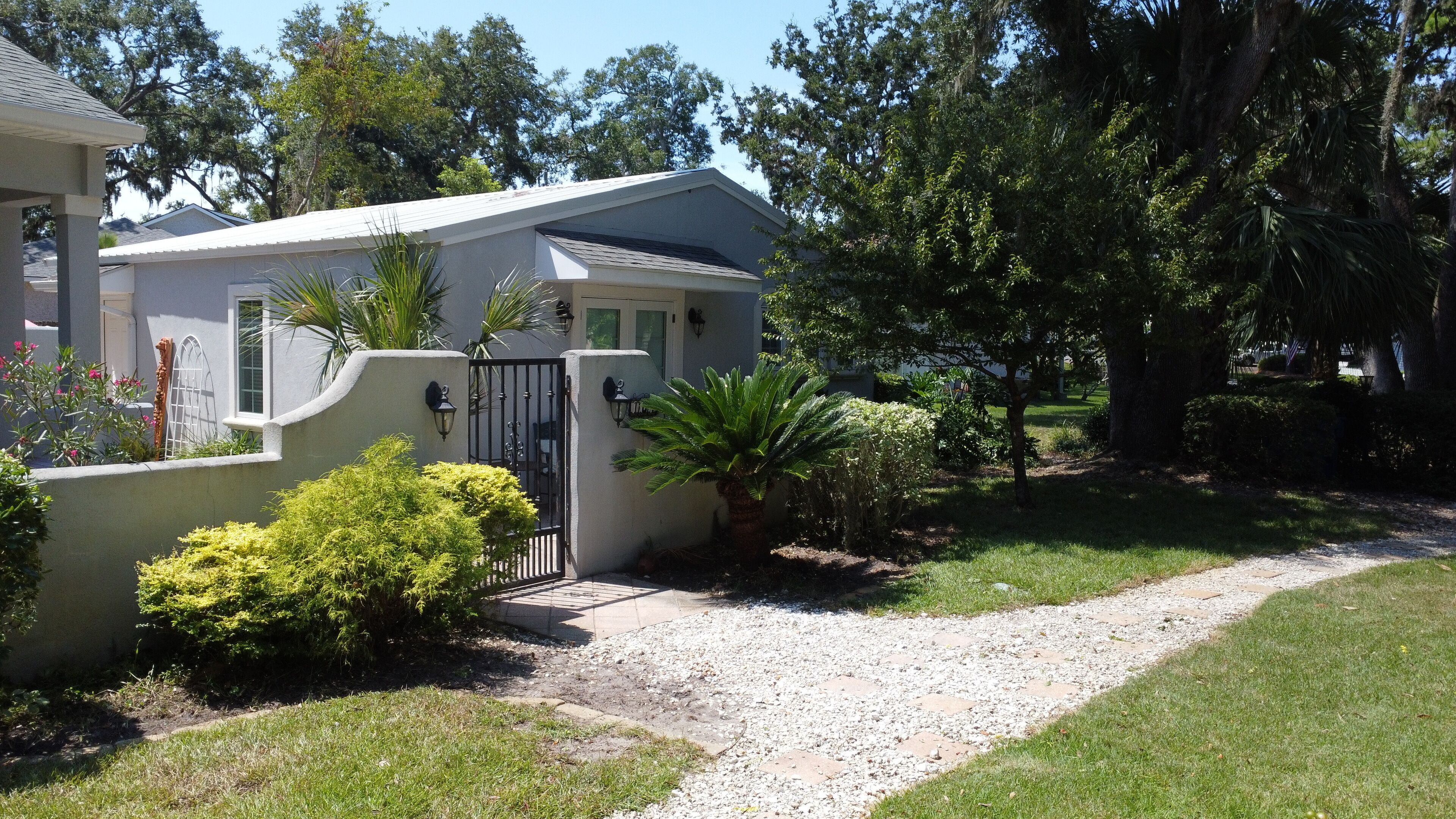 A residential property with a gated entrance, a gravel driveway, and a well-maintained lawn.