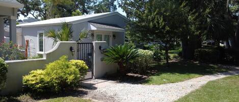 A residential property with a gated entrance, a gravel driveway, and a well-maintained lawn.