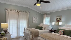 Une chambre avec deux lits, un bureau, une lampe et un ventilateur de plafond.