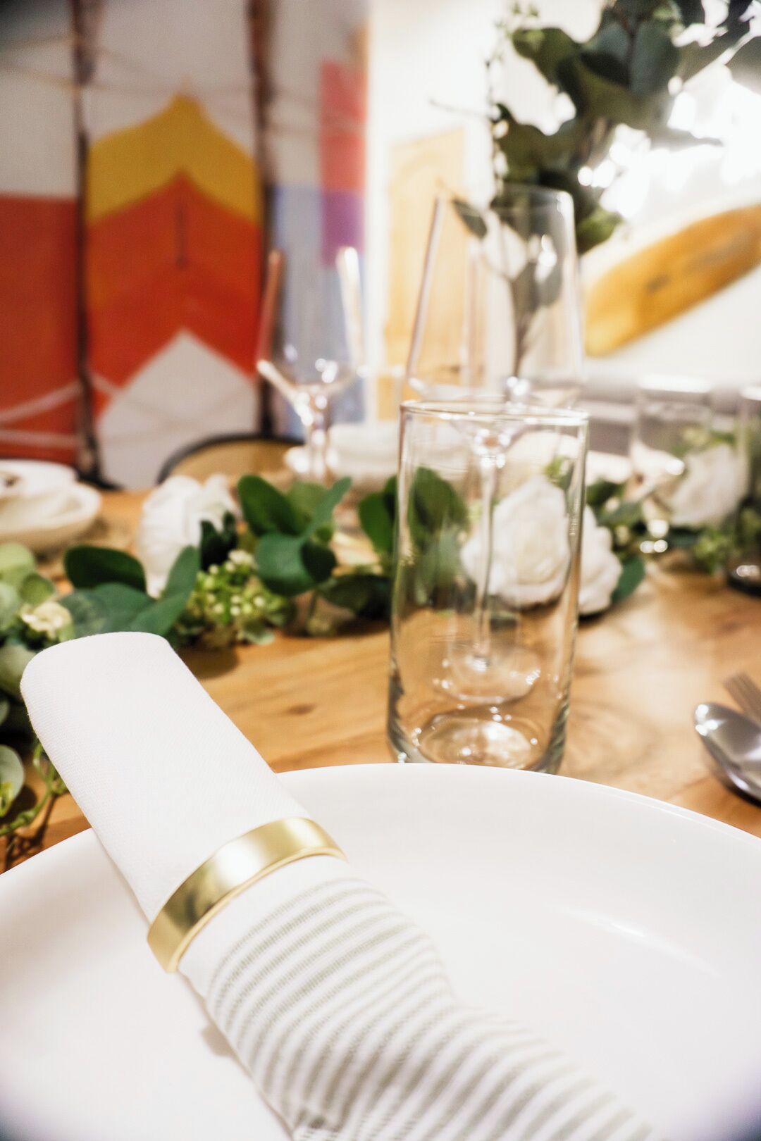 A dining table with a white napkin, a gold band, and a glass.
