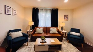 A living room with a brown leather sofa, two blue armchairs, a coffee table, and two side tables with lamps. - No cleanup chores-Fenced yard, fire pit. Close to I81, downtown. Walk to casino. (Bristol)