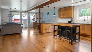 A spacious kitchen with wooden cabinets, a central island with stools, and a dining area with a sofa and chairs.