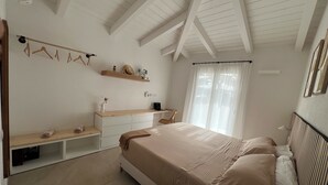 A bedroom with a bed, a desk, and a chair. There is a window with curtains, a shelf with decorative items, and a hanging light fixture. - Villa Sisine, 🏊 Private pool, Just a 5-Minute Walk from the Beach (Sardegna)