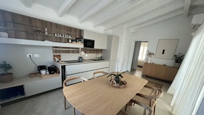 A modern kitchen with white cabinets, a wooden dining table, and a built-in oven. - Villa Sisine, 🏊 Private pool, Just a 5-Minute Walk from the Beach (Sardegna)