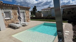 A swimming pool with lounge chairs and a stone wall. - Villa Sisine, 🏊 Private pool, Just a 5-Minute Walk from the Beach (Sardegna)