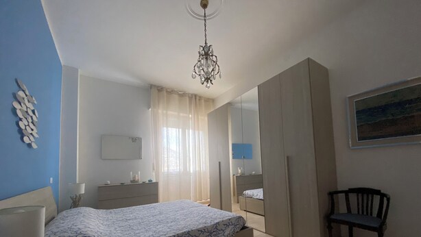 Ein Schlafzimmer mit Bett, Stuhl, Kommode, Spiegel und einem Bild an der Wand.