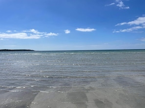 A beach with clear water and a distant landmass.