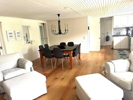 A modern living room with a dining table, two sofas, and a chandelier.