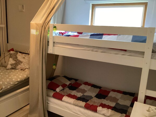 A bunk bed with a lower bunk and a window above it.
