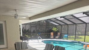 A covered patio with a pool, outdoor furniture, and a view of the backyard.