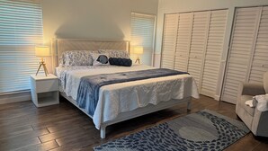 A bedroom with a bed, nightstands, a ceiling fan, and a wardrobe.