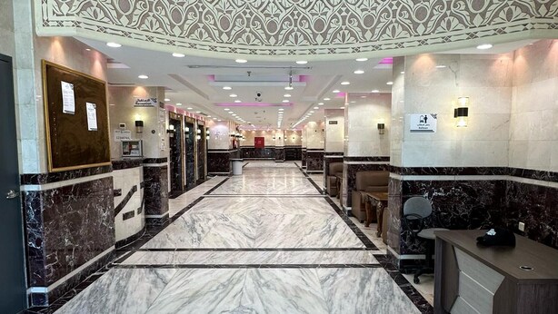 A hotel lobby with a marble floor, reception desk, seating area, and a decorative ceiling. - Mashrab Riwa Almansour Hotel (Makkah)