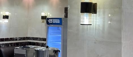 A cafe area with a marble counter, a coffee machine, a General Supreme coffee machine, and a wall-mounted light fixture.