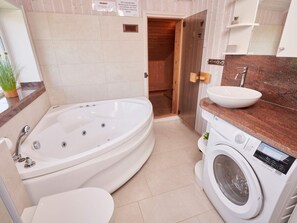 A modern bathroom with a freestanding bathtub, a built-in sink, and a front-loading washing machine. - 4 Star Holiday Home in Friedrichkoog (Friedrichskoog)