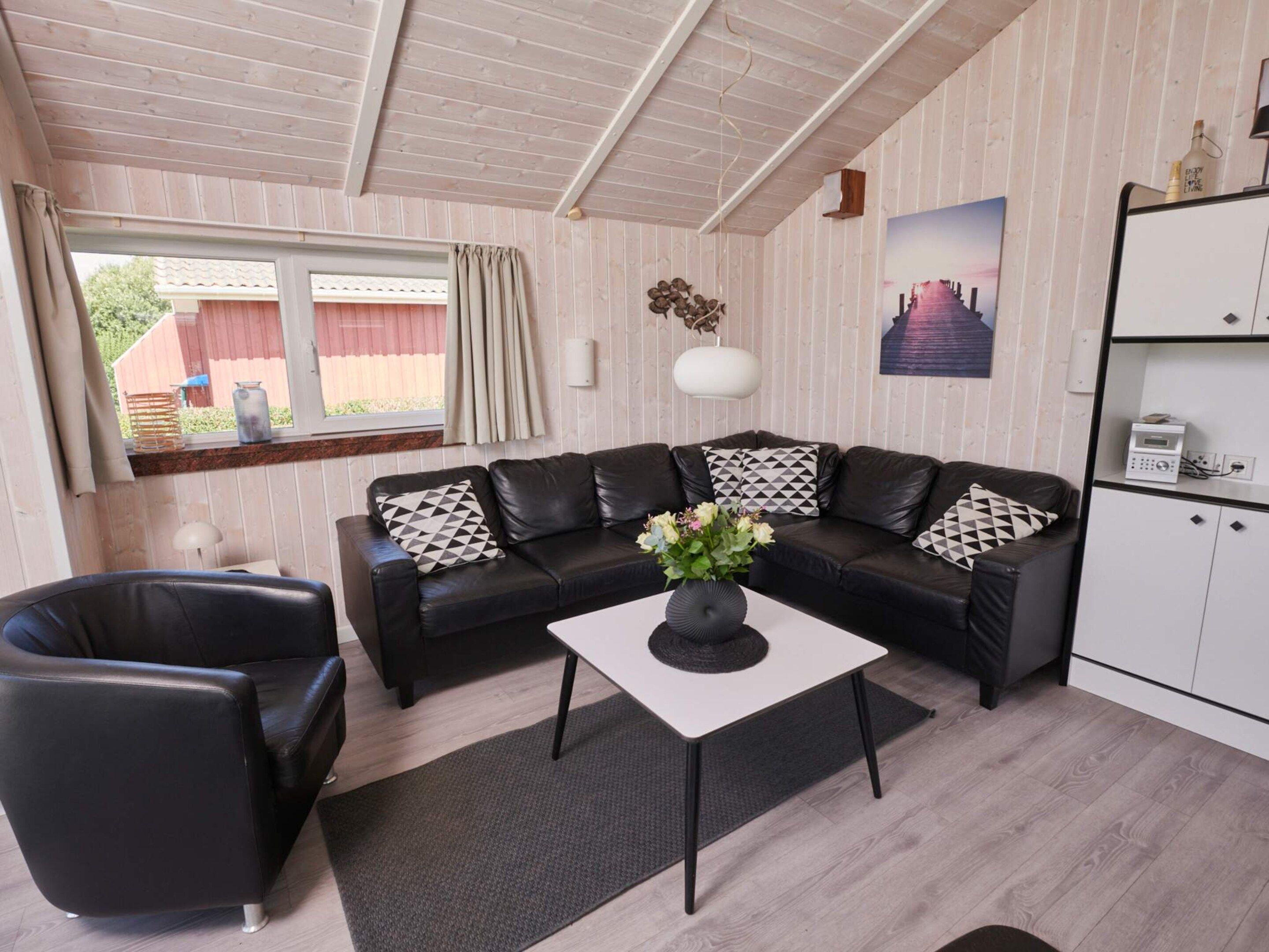 A living room with a black leather sofa, a white coffee table, and a black armchair.