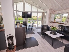 Un intérieur moderne comprenant un coin repas, un canapé, un téléviseur et une vue sur l’extérieur.